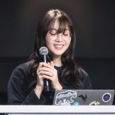 Lauren Tan speaking into a microphone behind a laptop in the portrait supplied for her Maven workshop